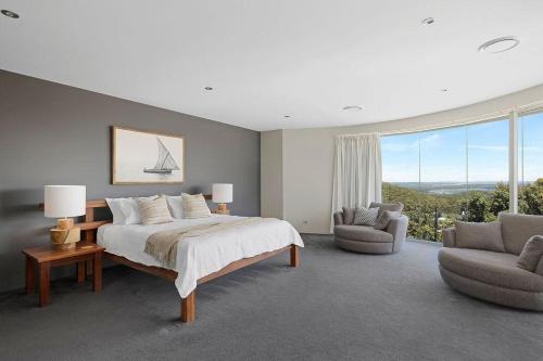 a bedroom with a large bed and a large window at Grandview - Luxurious Entertainer with Spectacular Views in Nelson Bay