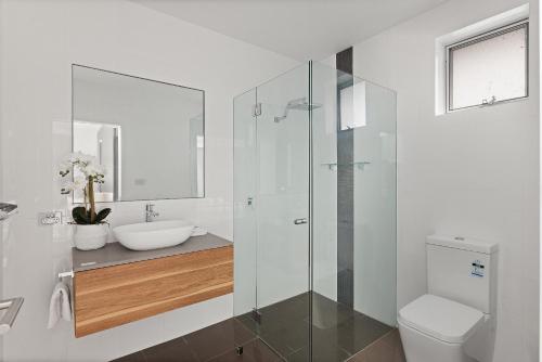 a white bathroom with a sink and a toilet at Grandview - Luxurious Entertainer with Spectacular Views in Nelson Bay