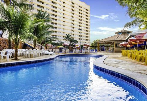 una piscina con sillas y sombrillas frente a un hotel en Flat Golden Dolphin Grand Hotel - Quarto e Sala Com Roupa de Cama e Banho - Piscinas 24h en Caldas Novas