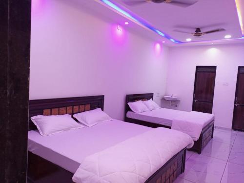 two beds in a room with purple lights at SARDAR HOME STAY in Garudeshwar