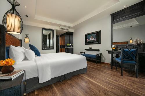 a bedroom with a large white bed and a desk at Shining Riverside Hoi An Boutique & Spa in Hoi An