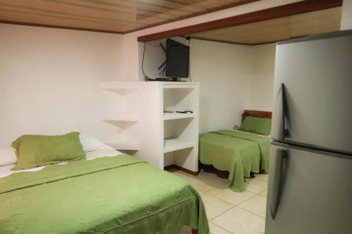 a small room with two beds and a refrigerator at Hotel Hoja de Oro Corcovado in Puerto Jiménez