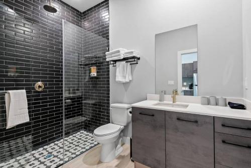 a bathroom with a toilet and a shower with black tiles at Pretty Rola 304 Luxury Apt w King Bed Central Area in Fort Lauderdale