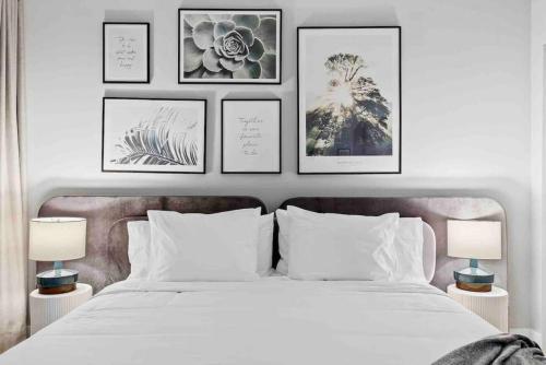 a bedroom with a white bed with four pictures on the wall at Pretty Rola 304 Luxury Apt w King Bed Central Area in Fort Lauderdale