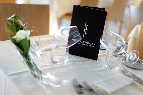 a table with wine glasses and a menu on it at Hotel Europa Lignano in Lignano Sabbiadoro