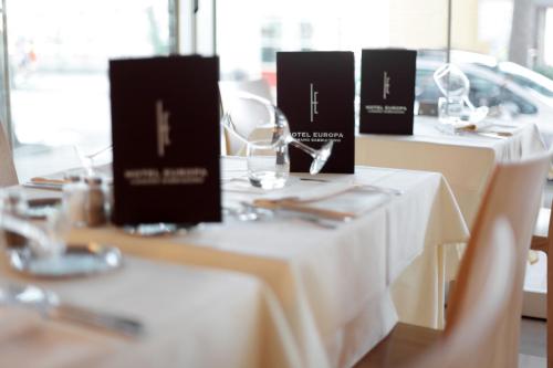 two tables with white table cloths on them in a restaurant at Hotel Europa Lignano in Lignano Sabbiadoro