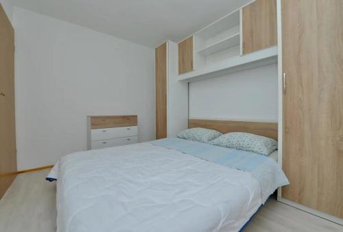 Apartments by the sea Tkon, Pasman - 19017 في تكون: غرفة نوم بسرير أبيض وخزانة خشبية