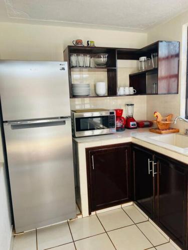 a kitchen with a refrigerator and a microwave at Amplio Dpto. céntrico con cochera y terraza. in San Cristóbal de Las Casas