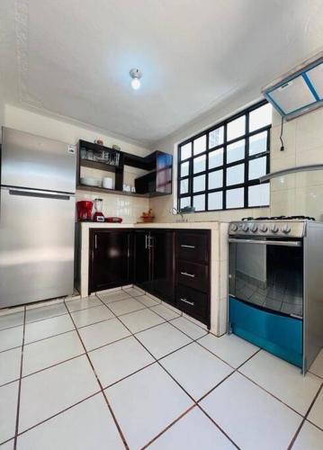 a kitchen with stainless steel appliances and white tile floors at Amplio Dpto. céntrico con cochera y terraza. in San Cristóbal de Las Casas