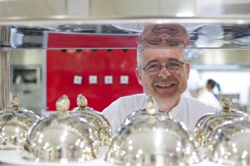 a man in a kitchen with a bunch of silver dishes at La Côte Saint Jacques in Joigny