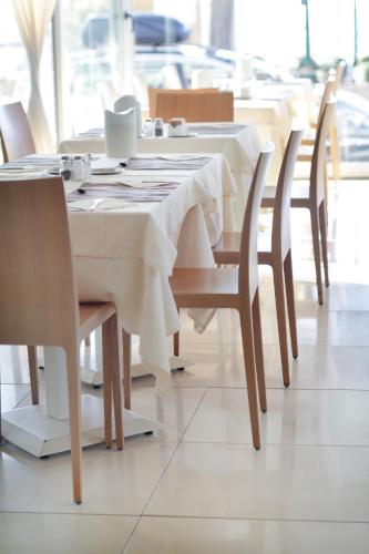 a table in a restaurant with white tables and chairs at Hotel Europa Lignano in Lignano Sabbiadoro