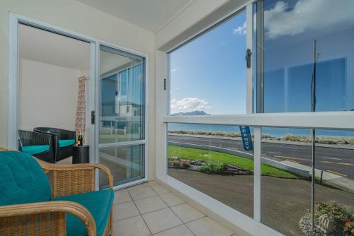 a living room with sliding glass doors with a view of the ocean at Waterfront Apartments Whitianga in Whitianga
