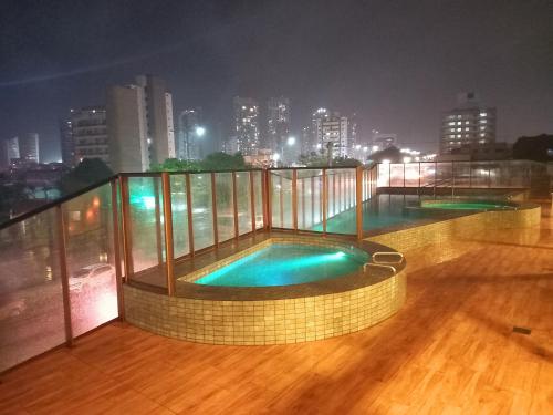 a swimming pool on the roof of a building at night at Ilusion Flats Aconchego de Ponta Negra in Natal
