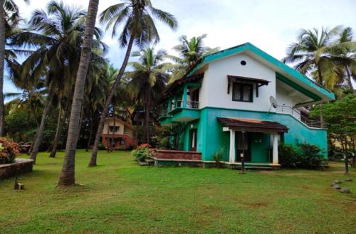 una casa verde y blanca con palmeras en Miramar Residency, en Panaji