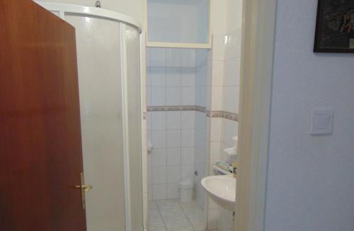 Apartments by the sea Seget Donji, Trogir - 19351 في تروغير: حمام مع دش ومغسلة ومرحاض