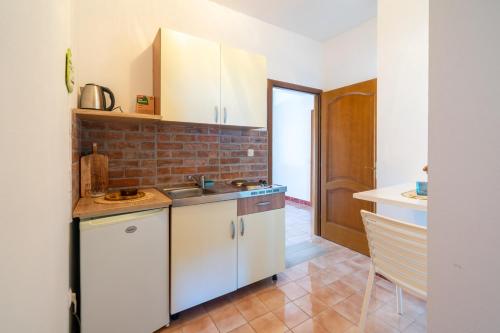 a kitchen with white cabinets and a brick wall at Apartments by the sea Lun, Pag - 19358 in Lun