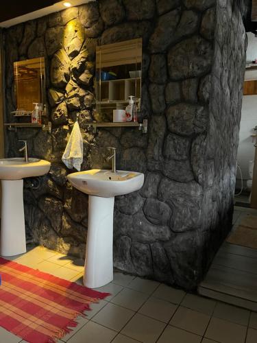 a bathroom with two sinks and a stone wall at Escape Backpackers KK in Kota Kinabalu