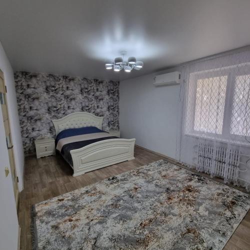 1 dormitorio con cama y alfombra en Квартира у моря, en Aktau
