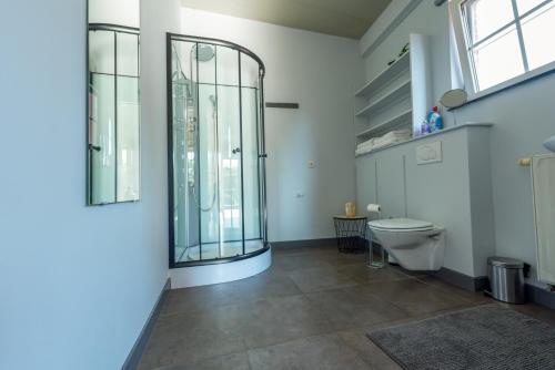 a bathroom with a toilet and a glass shower at Vakantiewoningen Pomona in Heers