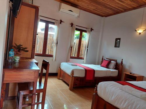 a room with two beds and a table and a desk at Villa Rattanakon in Luang Prabang