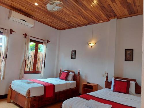 a bedroom with two beds and a wooden ceiling at Villa Rattanakon in Luang Prabang