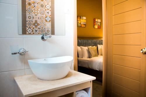 een badkamer met een witte wastafel en een bed bij Hotel Horizon Entebbe in Entebbe
