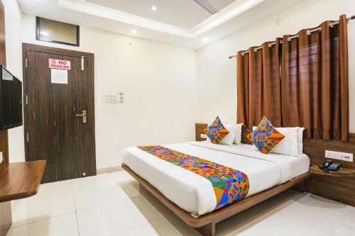 a bedroom with a bed and a wooden door at FabHotel Balaji Paradise in Indore