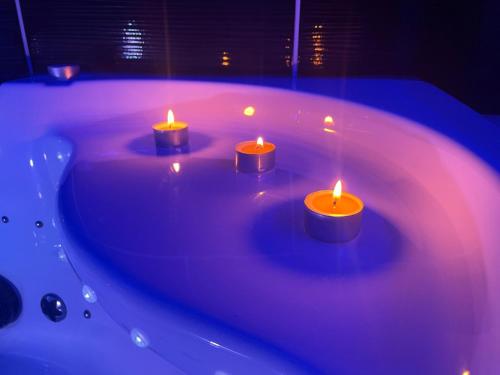 4 bougies assises dans une baignoire éclairée dans l'établissement NG SuiteHome - Lille I Tourcoing Winoc - Balnéo - Netflix - Wifi, à Tourcoing
