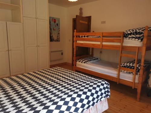 1 dormitorio con 2 literas y suelo a cuadros en Ground Floor Slievemore Apartment, en Bellanasally