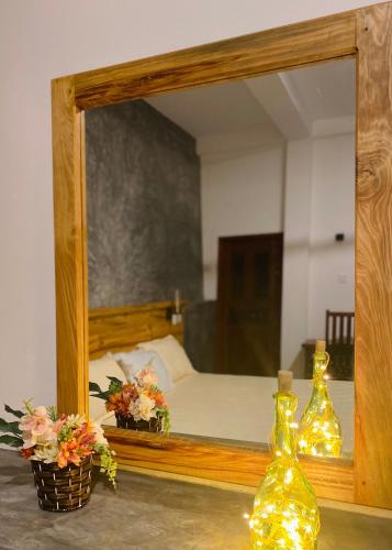 a mirror with two bottles on a table in front of a bed at The Cozy Nest in Hikkaduwa