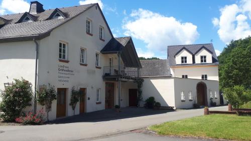a white building with a gate and a house at Landhaus Gräfendhron in Gräfendhron