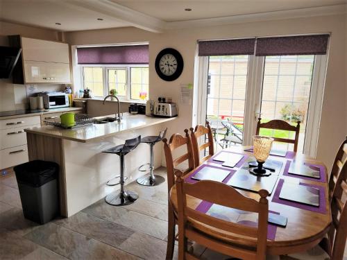 een keuken en eetkamer met een tafel en een klok bij Smitten House 4 Bedroom RHYL in Rhyl