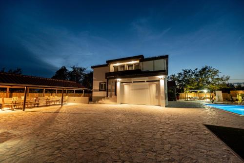 a house with a garage and a swimming pool at night at Villa Heaven in Donji Zemunik