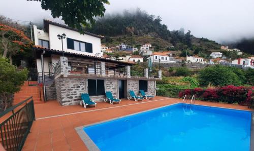 a villa with a swimming pool in front of a house at Casa Gama in Ribeira Brava