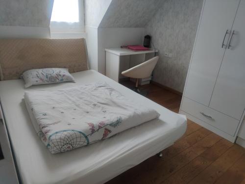 a small bedroom with a white bed and a desk at Chambre privée à Bobigny -salle de bain et toilettes sont commune, -pas de cuisine in Bobigny