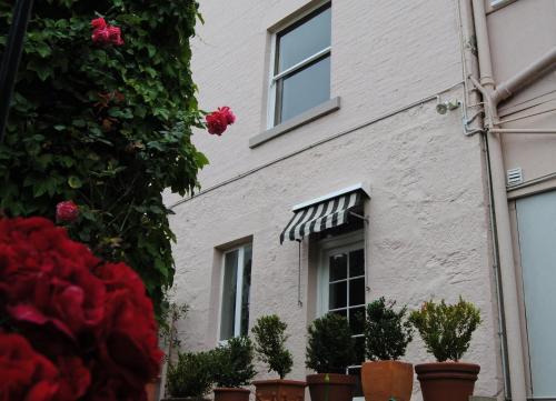 a white building with a window and potted plants at Maison del Mar in Hobart