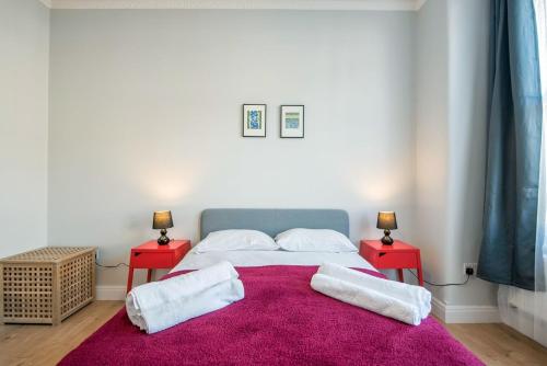 Comfortable flat in Hammersmith في لندن: غرفة نوم مع سرير وطاولتين حمراء