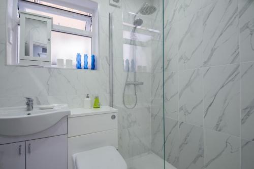 a white bathroom with a shower and a sink at Comfortable flat in Hammersmith in London