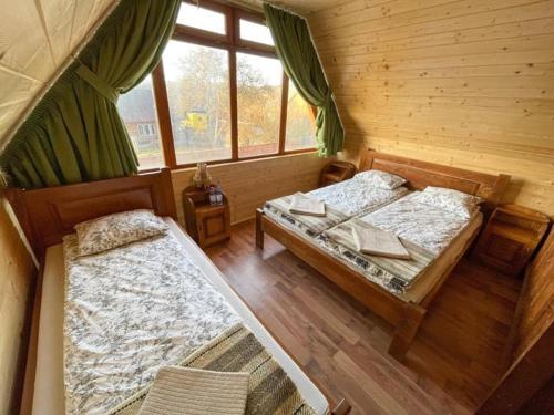 a bedroom with two beds in a log cabin at Varság Gyöngye Vendégház in Vărşag