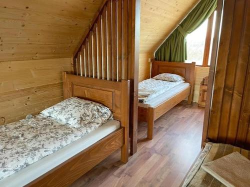 two beds in a cabin with wooden walls at Varság Gyöngye Vendégház in Vărşag
