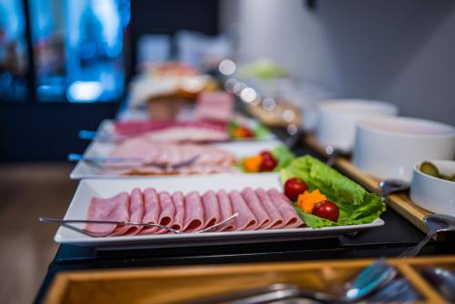 a buffet line with plates of meats and vegetables at GLAMOUR - Restaurant & SPA in Przeźmierowo