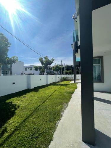 a white fence with a green lawn next to a building at 福氣安康 Ray’s Homestay in Batu Pahat