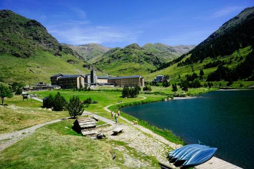 um lago com um edifício e um barco na costa em Hotel Vall de Núria em Queralbs