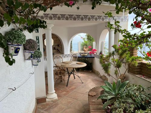 un patio con mesa, sillas y plantas en Casa Hermosa, en Torre de Benagalbón