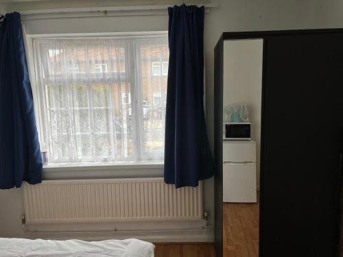 um quarto com uma janela com cortinas azuis em Large Double Bedroom with free on site parking em Kingston upon Thames