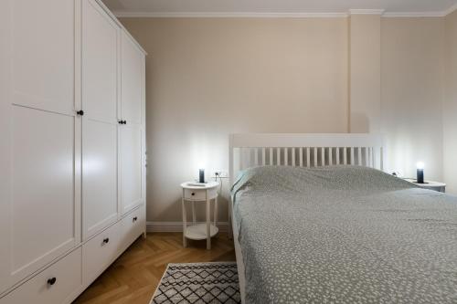 a white bedroom with a bed and a night stand at Joy City Stay Victoriei 7D-8 in Timişoara