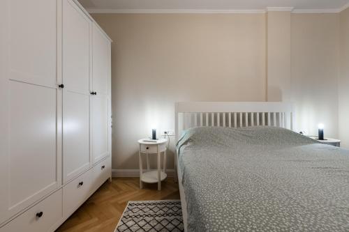 a white bedroom with a bed and a night stand at Lovely flat, UltraCentral, with Free Parking VIC8 in Timişoara