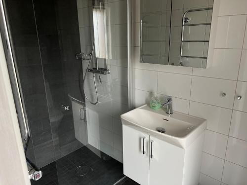 a white bathroom with a shower and a sink at Nice apartment, rural idyll just outside Karlstad in Karlstad