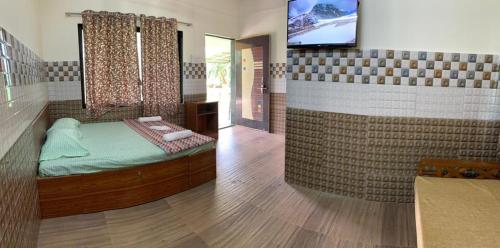 um quarto com uma cama e uma televisão na parede em Sarovar's Nest em Avas