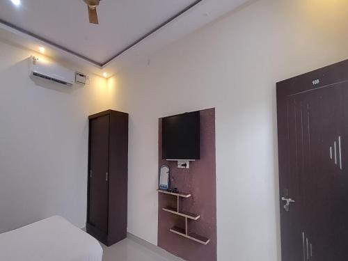a room with a bed and a tv on a wall at MG Residency in Chikmagalūr